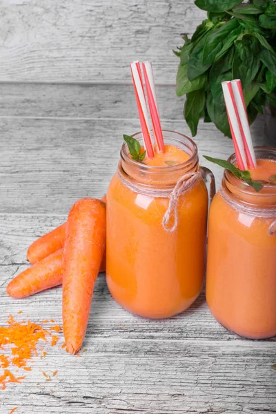 Mason kavanoza gri ahşap masa arka plan üzerinde sağlıklı havuç içecek dolu. 