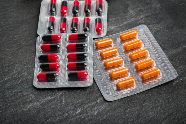 Pacotes com tablets coloridos em um fundo de mesa cinza. Narcóticos farmacêuticos. Conceito de saúde . — Fotografia de Stock