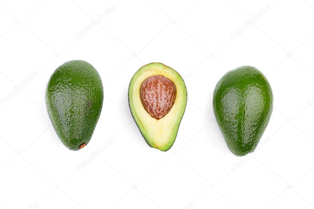 A top view of two whole green avocados and one cut in half in a center, isolated on a white background. A fresh, natural and ripe avocado with a large stone. Three healthful fruits in a row.