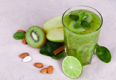 Baharatlı nane ve masa lambası arka plan üzerinde taze elma ile bir parlak yeşil kivi güler yüzlü. Yeşil yaprakları ve besleyici badem fındık ile yarım kivi kesti. Vejetaryenler için meyve kokteylleri.