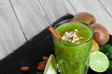 Yakın çekim resmi bir doymuş yeşil alkolsüz kokteyl gevrek fındık, kivi meyve ve ahşap arka plan aromatik tarçın ayakta. Tropikal kivi ve taze dilimlenmiş limon.