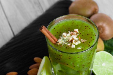 Yakın çekim resmi bir doymuş yeşil alkolsüz kokteyl gevrek fındık, kivi meyve ve ahşap arka plan aromatik tarçın ayakta. Tropikal kivi ve taze dilimlenmiş limon.