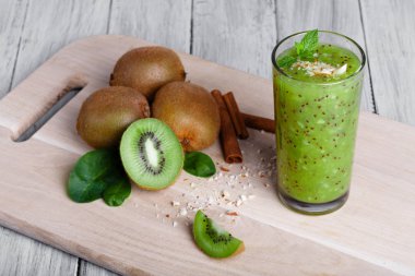 Bir üstten görünüm kivi meyve besleyici vitaminler, tarçın ve ceviz dolu bir kesme tahtası ve gri bir ahşap arka plan. Organik yeşil güler yüzlü sulu kivi, rendelenmiş fındık ve nane.