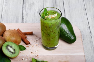 Sağlıklı, taze yeşil kivi smoothie egzotik meyve kivi meyve, avokado, ceviz, tarçın ve gri bir ahşap zemin, üstten görünüm üzerine nane ile üzerinden. Tarçın, avokado ve kivi bir masa üzerine.