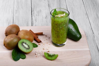 Sağlıklı, taze yeşil kivi smoothie egzotik meyve kivi meyve, avokado, ceviz, tarçın ve gri bir ahşap zemin, üstten görünüm üzerine nane ile üzerinden. Tarçın, avokado ve kivi bir masa üzerine.