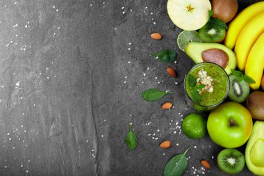 Tropikal meyve çeşitleri en iyi görünümü geniş tablo arka plan üzerinde. Kazık muz, avokado, Sulu kireç, kivi ve elma kesmek. Bir bardak meyve suyu baharat ve badem ile. Kopya alanı.