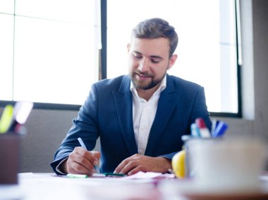 Genç bir işadamı belgeleri masasında imzalar..