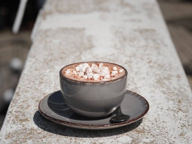 Bir close-up marshmallow ile sıcak çikolata tam bir eski porselen kupa. Bir taş zemin üzerine tatlı kapuçino. Yuvarlak bir plaka ile bir fincan. Uzay kopyalayın. Gevşeme, Kahvaltı konsepti.