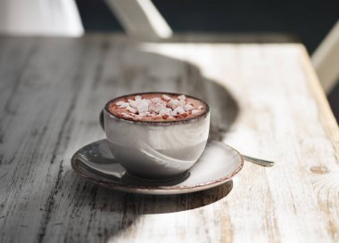 Bir gri porselen kupa ile beyaz marshmallow sıcak çikolata tam bir yakın çekim resim. Tatlı kapuçino gri ahşap masa arka plan üzerinde. Metal bir kaşık ile bir fincan. Uzay kopyalayın. Kahvaltı konsepti.