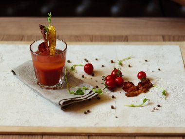 Kiraz domates, güzel kokulu peppercorns ve otlar en iyi görünümünü ahşap bir masa üzerinde hafif kumaş üzerinde. Bloody Mary bir bardak pastırma ve patates bir üst arka plan bulanık bir cam dilim ile.