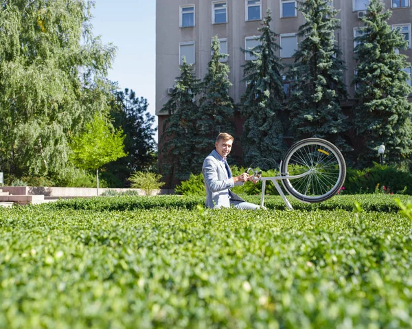 Genç bir adam Onun Bisiklet yönetiminin bahçedeki rafta yükseltir — Stok fotoğraf
