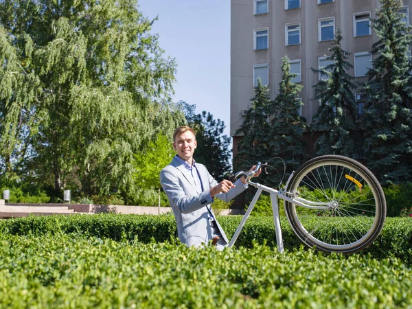 Un joven levanta su bicicleta en el estante en el jardín de la administración — Foto de Stock