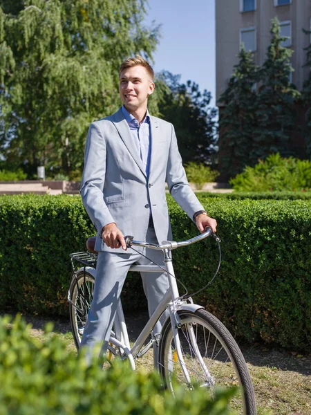 Un tipo en un hermoso traje en una bicicleta pasea por la calle — Foto de Stock