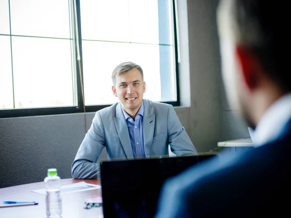 Young man in suit, at desk in office. Close-up .