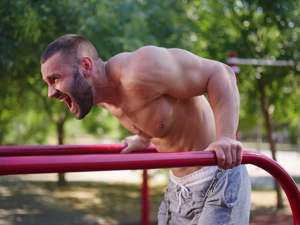 Atlético, homem bonito sexy fisiculturista trabalhando em um fundo turvo. Construção muscular conceito . — Fotografia de Stock