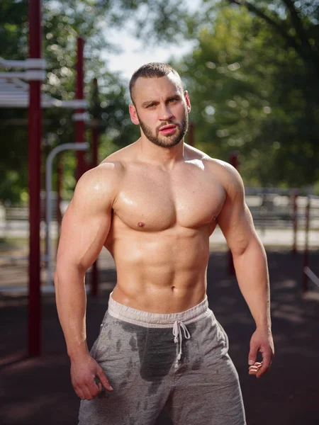 Sexy en gespierde shirtless bodybuilder man pronken op een onscherpe achtergrond. Uitwerken concept. — Stockfoto