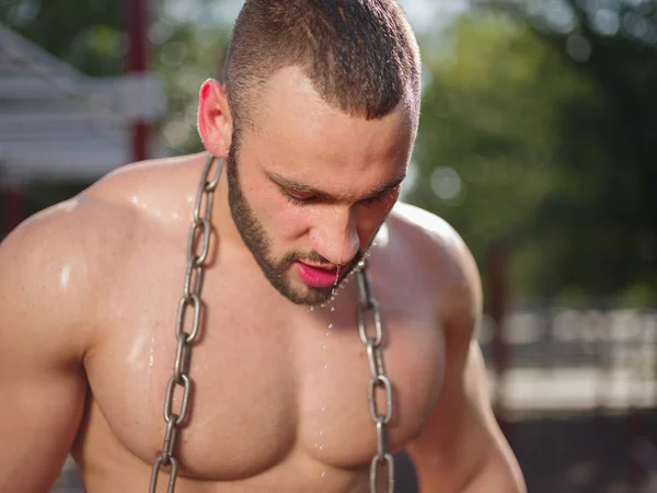 Красивий, здоровий, м'язистий спортивний чоловік з металевим ланцюгом на розмитому тлі. Концепція важкої ваги . — стокове фото
