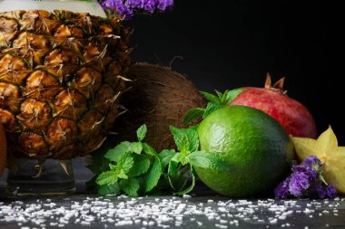 Tropikal meyve üzerinde arka planı gri taş ayarla close-up. Parlak avokado, sarı carambola, olgun garnet, egzotik Hindistan cevizi ve tropikal ananas. 