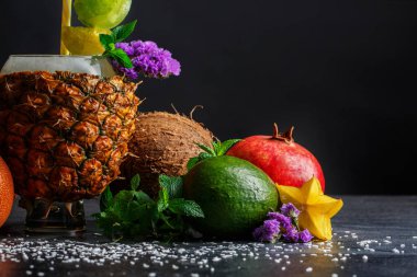 Tropikal meyve üzerinde arka planı gri taş ayarla close-up. Parlak avokado, sarı carambola, olgun garnet, egzotik Hindistan cevizi ve tropikal ananas. 