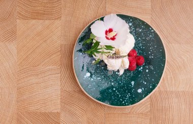 Bir taze ve soğuk vanilya tatlı tatlı Ahududu ve nane hafif ahşap zemin ile bir plaka üzerinde bir görünüm yukarıdan. Dondurma kaşık toz bir dekoratif çiçek.