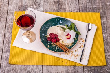 Bir sağlıklı restoran tatlı kümesi. Beyaz dondurma bir orkide çiçeği, olgun çilek, tarçın ve taze nane ile bir kase. Bir tatlı ve bir kadeh şarap ahşap masa arka plan üzerinde.