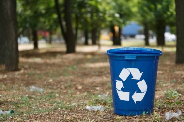 Bir parlak koyu mavi Geri Dönüşüm Kutusu'na park veya ahşap. Renkli plastik konteyner bir bulanık doğal arka plan üzerinde geri dönüşüm çöp için. Çevre, ekoloji, doğa koruma, kirliliği kavramı.