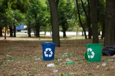 Birkaç parlak mavi ve yeşil park depo gözleri geri dönüşüm. Plastik çöp konteynırları yanındaki plastik şişe doğal arka plan bulanık. Çevre, ekoloji geri dönüşüm kirliliği kavramı,.