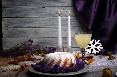 Açık gri ahşap renkli bir yeni yıl Gıda kompozisyonu. Toz şeker, meyveli içecek, tarçın ve mumlar bir tatil tablo olan bir ev yapımı vanilyalı pasta. Kopya alanı.