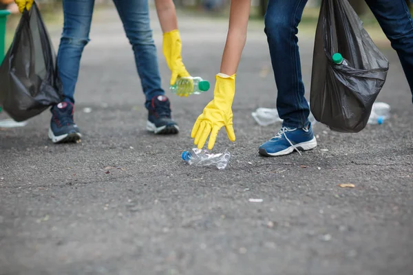 子供の足と黄色のラテックス手袋の手のクローズ アップ画像 プラスチックのゴミを拾う子供たちのカップル エコロジー 自然保護 汚染概念 コピー スペース — ストック写真