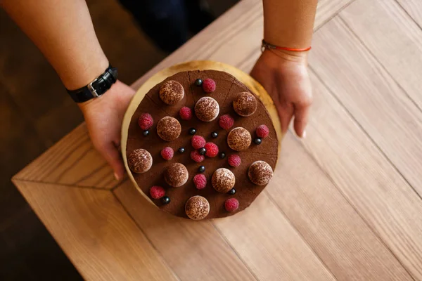 bir kadının yukarıdan görünüm ahşap arka plan kremsi bir katmanda bir lezzetli çikolatalı kek, ellerimi.