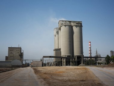 Tipik Üretici Fabrika mavi gökyüzü arka plan üzerinde. Büyük bir gri bina ve Metalurji bir bitkinin çizgili bir baca. Endüstriyel fabrika. Hava kirliliği, ekoloji kavramı. Kopya alanı.