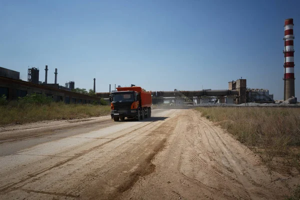 Makine ekipman ile bir doğal kum ocağı arka plan yüklü bir yere. Sürüş kumlu bir yolda bir büyük portakal ışınlama. Teknoloji, kargo, ticaret, ulaşım kavramı. Kopya alanı.