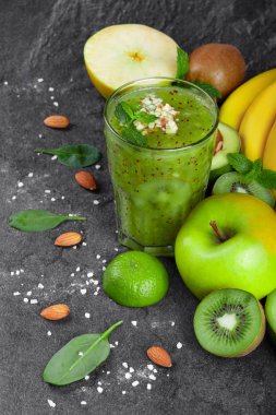 Yukarıdan bir bileşimi ile rendelenmiş fındık tepesinde ve olgunlaşmış meyve kivi güler yüzlü bir karanlık arka plan taşlar. Bütün ve kesilmiş elma, limon, kivi, avokado ve olgun muz bir tabloda bir dalı.