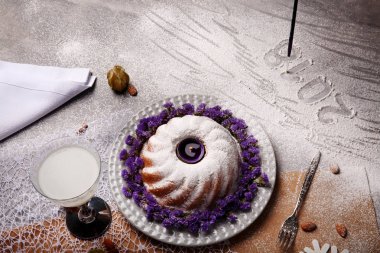 Yukarıdan bir Noel pudingi ile pudra şekeri serpilir ve açık gri renkli çiçekler ile dekore edilmiştir. Bir tatil 's pasta ve Hindistan cevizi sütü bir tablo. Yılbaşı Dekorasyonu. Kopya alanı.