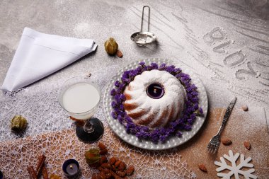 Yukarıdan bir Noel pudingi ile pudra şekeri serpilir ve açık gri renkli çiçekler ile dekore edilmiştir. Bir tatil 's pasta ve Hindistan cevizi sütü bir tablo. Yılbaşı Dekorasyonu. Kopya alanı.