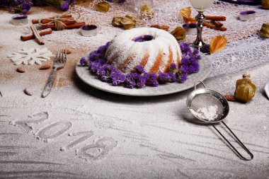 Pişmiş kek ve organik hindistan cevizi içecek gri bir arka plan üzerinde güzel bir Noel kompozisyon. Bir tatil 's pasta buzlanma ile ve ihale mor çiçekler. Tarçın ve badem bir tablo.