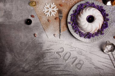 Yukarıdan görünüm geleneksel vanilya Noel kek pudra şekeri ve dekoratif çiçek çanak üzerinde gri bir arka plan etrafında serpilir. Tatil 's pasta yakınındaki bir kar tanesi. Yeni yıl 2018.