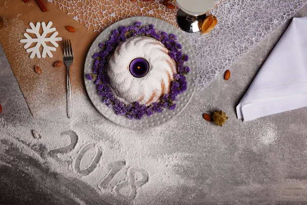 Yukarıdan görünüm geleneksel vanilya Noel kek pudra şekeri ve dekoratif çiçek çanak üzerinde gri bir arka plan etrafında serpilir. Tatil 's pasta yakınındaki bir kar tanesi. Yeni yıl 2018.