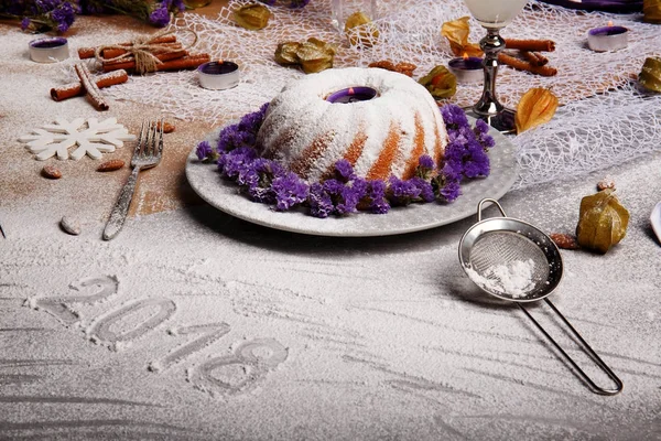 Pişmiş kek ve organik hindistan cevizi içecek gri bir arka plan üzerinde güzel bir Noel kompozisyon. Bir tatil 's pasta buzlanma ile ve ihale mor çiçekler. Tarçın ve badem bir tablo.