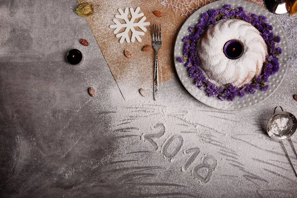 Yukarıdan görünüm geleneksel vanilya Noel kek pudra şekeri ve dekoratif çiçek çanak üzerinde gri bir arka plan etrafında serpilir. Tatil 's pasta yakınındaki bir kar tanesi. Yeni yıl 2018.