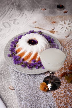 Bir tatlı Hindistan cevizi içecek üstten görünüm açık gri arka planı üzerinde. Noel pudingi ile pudra şekeri serpilir ve bir masaya çiçek ile dekore edilmiştir. Yılbaşı Dekorasyonu. Kopya alanı.