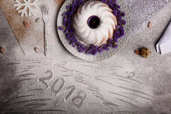 Yukarıdan görünüm geleneksel vanilya Noel kek pudra şekeri ve dekoratif çiçek çanak üzerinde gri bir arka plan etrafında serpilir. Tatil 's pasta yakınındaki bir kar tanesi. Yeni yıl 2018.