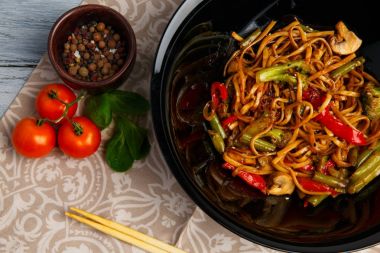 Geleneksel Çin yemeği yuvarlak tabakta, pirinç noodle, yeşil lahana lahana ve kızarmış sebzeler, kırmızı kiraz domates.