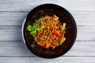 Geleneksel Çin yemeği yuvarlak tabakta, pirinç noodle, yeşil lahana lahana ve kızarmış sebzeler, kırmızı kiraz domates.