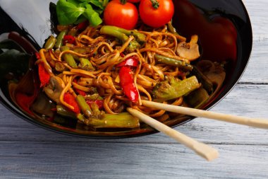 Geleneksel Çin yemeği yuvarlak tabakta, pirinç noodle, yeşil lahana lahana ve kızarmış sebzeler, kırmızı kiraz domates.