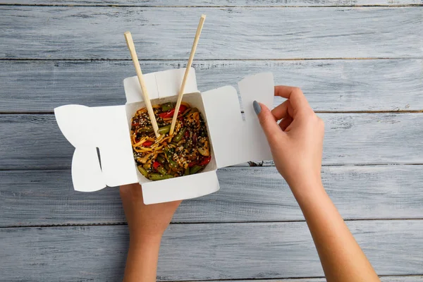 Noedels met kip en groenten in een doos. Vrouwelijke handen. Het concept van voedsel. — Stockfoto