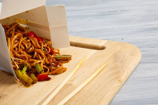 Kínai tészta egy doboz szürke asztalon. — Stock Fotó