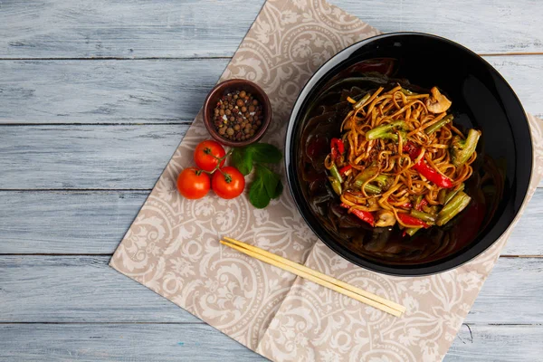Традиционное китайское блюдо на круглой тарелке, рисовая лапша, зеленая капуста и жареные овощи, красные помидоры черри . — стоковое фото