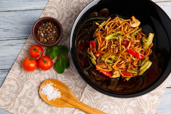 Geleneksel Çin yemeği yuvarlak tabakta, pirinç noodle, yeşil lahana lahana ve kızarmış sebzeler, kırmızı kiraz domates.