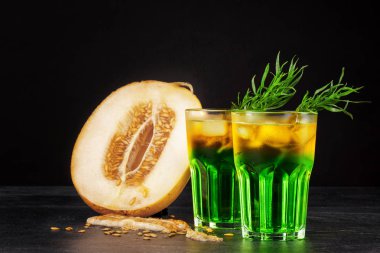 İki güzel alkollü buz, tarhun otlar ve kavun dilimleri siyah bir arka plan üzerinde bardak. Ferahlatıcı ve meyveli içecekler alkollü yaz. Taze kavun ve soğuk kokteyller. Kopya alanı.